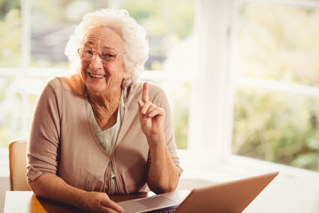 Foto van lachende oudere vrouw met een laptop