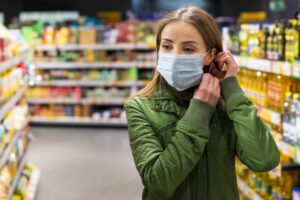 Foto van een jonge vrouw met mondkapje in een winkel