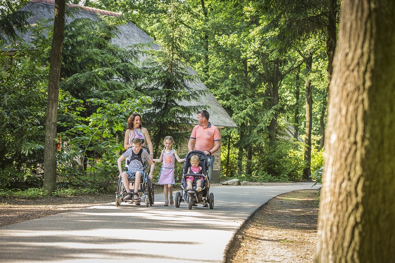 Foto van een wandelend gezin met een kind in een rolstoel