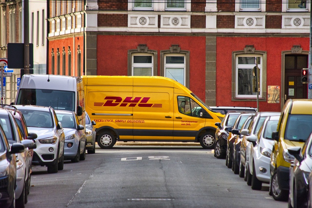 Foto van een gele DHL bestelbus in een straat