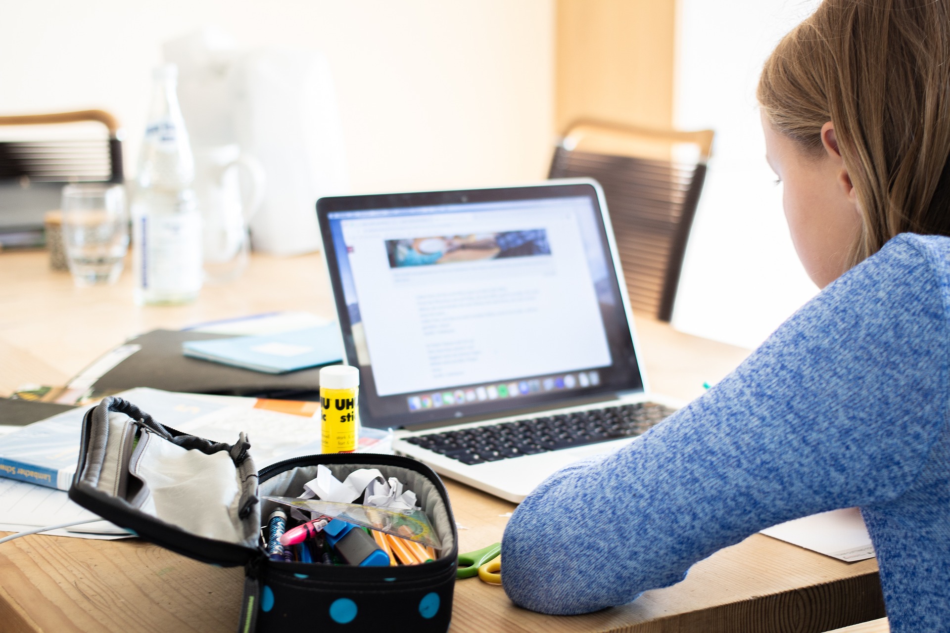 Foto van een jonge vrouw achter de laptop die een webinar volgt.