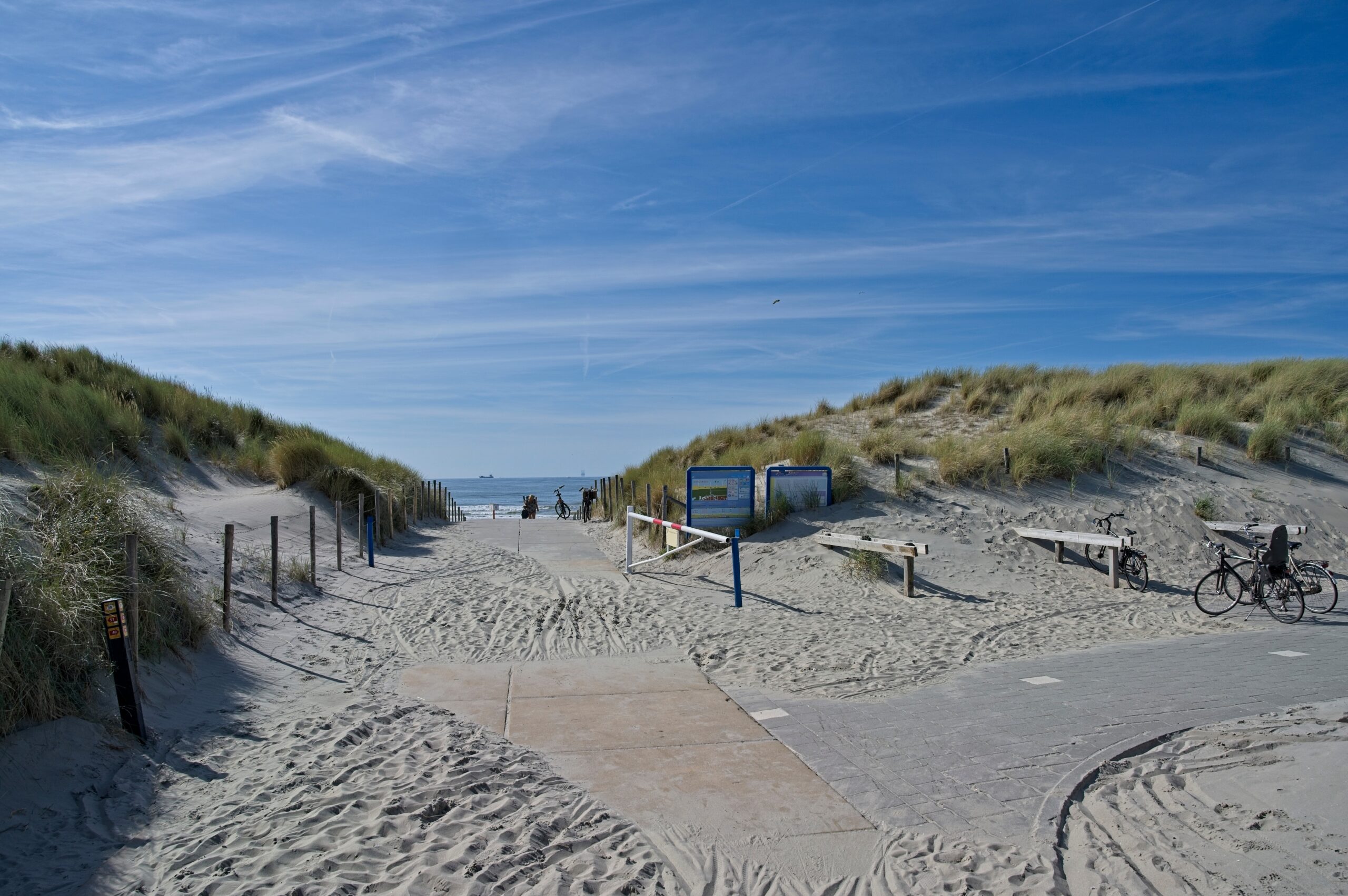 Foto van een duinpan met daarvoor een aantal betonplaten die ervoor zorgen dat het strand toegankelijk is voor iedereen.